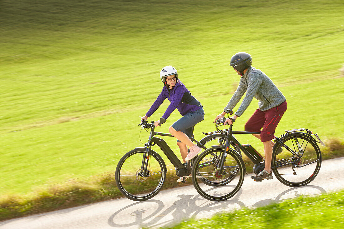 man and woman on eBikes, Muensing, Upper Bavaria, Germany