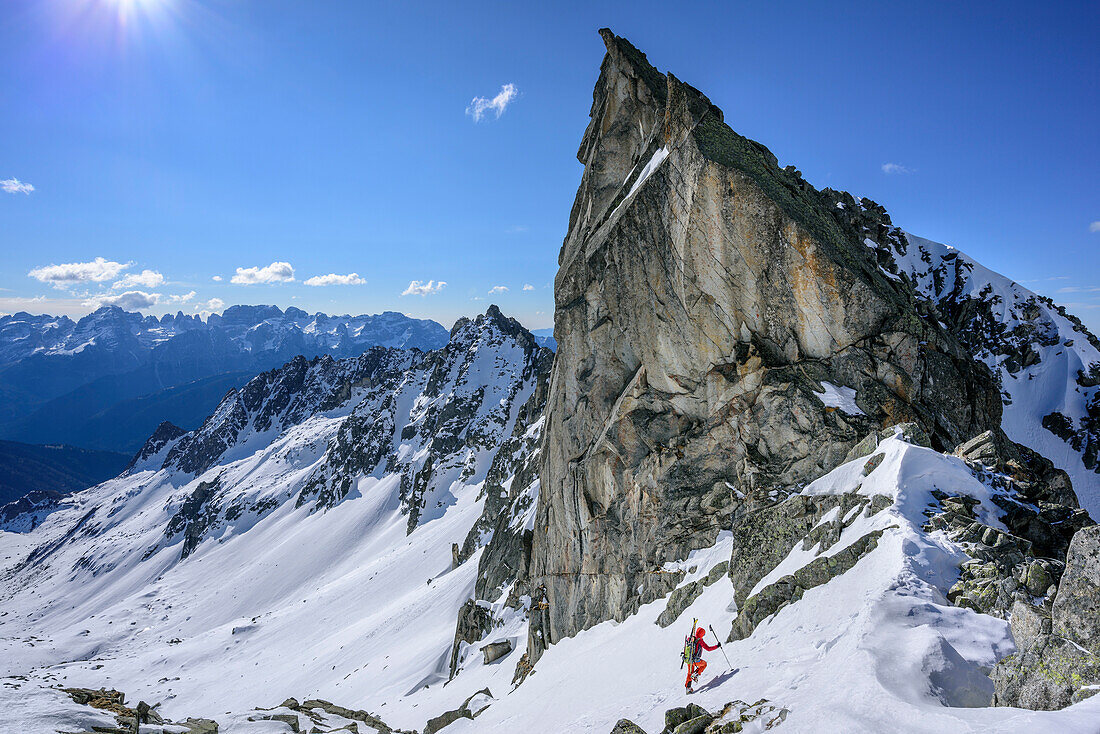 Frau auf Skitour steigt unter Felsturm hindurch zur Cima Presanella auf, Presanella, Adamellogruppe, Trentino, Italien
