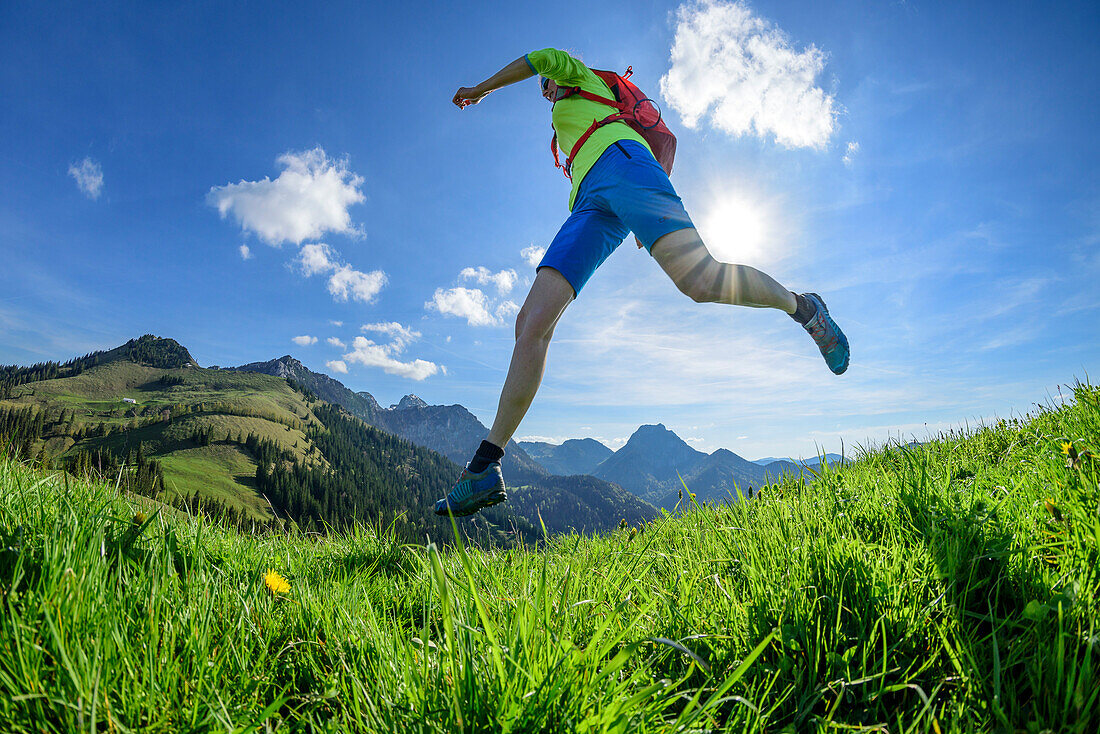 Woman trail running crossing meadow, Mitterberg, Bavarian Alps, Upper Bavaria, Bavaria, Germany