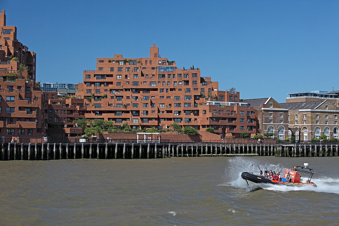 Touristenboot passiert einen Appartmentblock an der Themse, Wapping, London, England