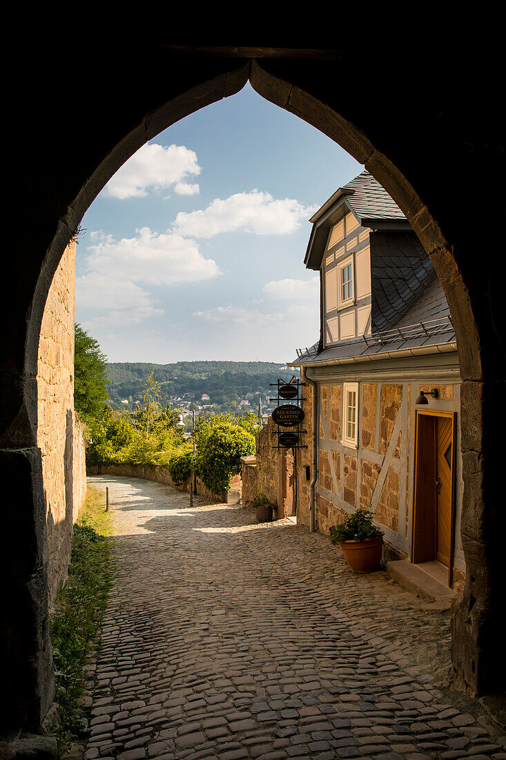 Blick durch das Schlosstor auf die steile Landgraf-Philipp-Straße mit einem Fachwerkhaus, Marburg, Hessen, Deutschland, Europa