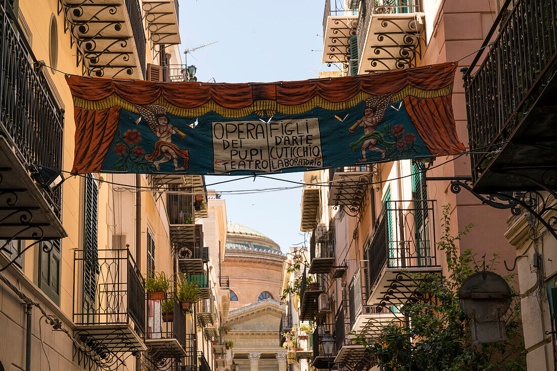 Artistic banner between two balconies in the narrow street Via Bara All'Olivella in front of Teatro Massimo Vittorio Emanuele theater on Piazza Verdi square, Palermo, Sicily, Italy, Europe