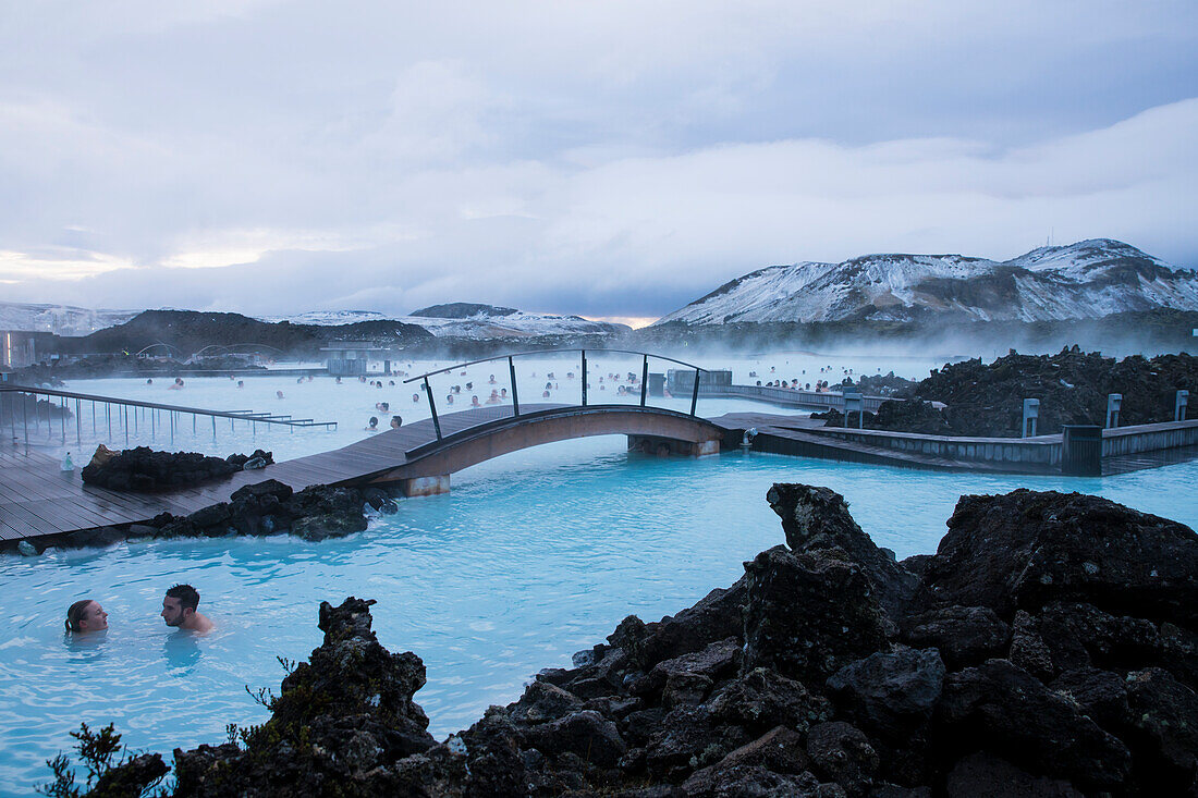 People bathe and swim at The Blue Lagoon, the famous wellness thermal pool with its typical blue-white water in winter time, near Grindavik, Reykjanes, Iceland, Europe