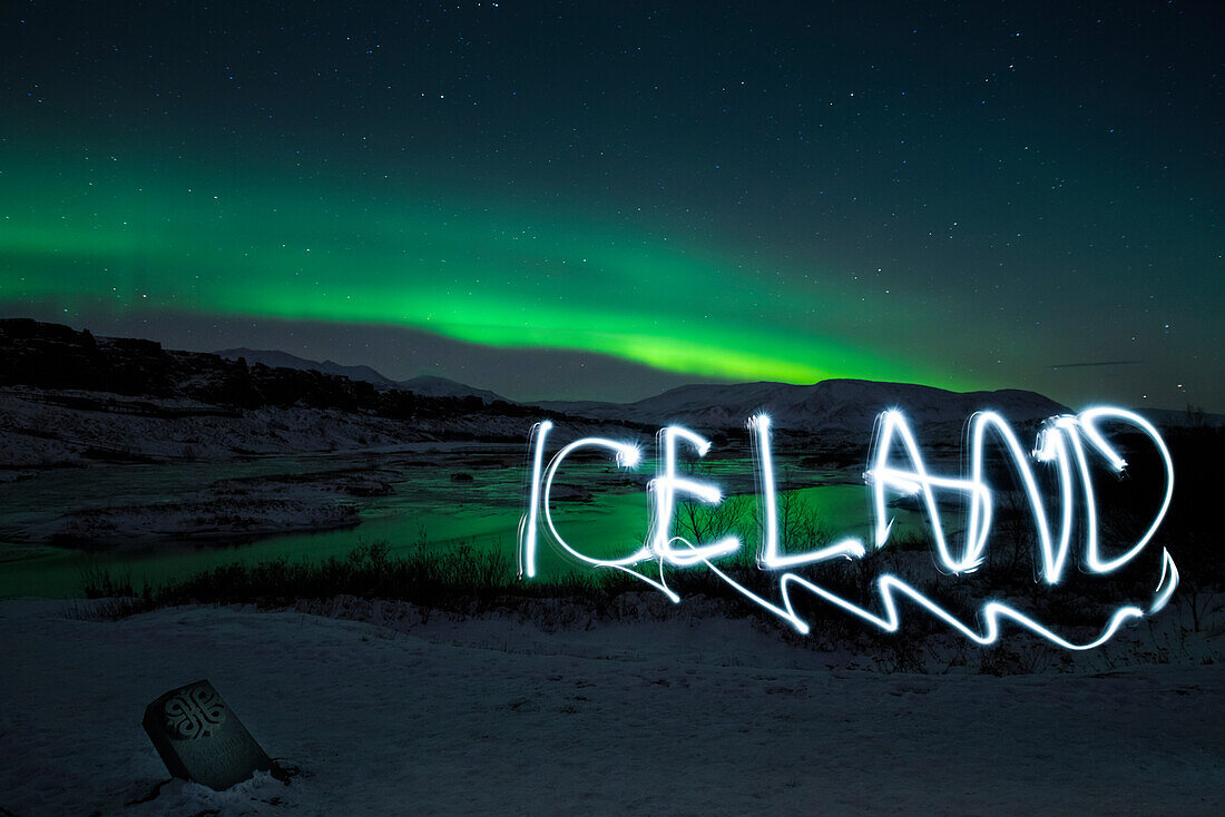 'Mit Taschenlampe geschriebener Licht Schriftzug ''Iceland'' vor Kulisse aus Landschaft mit Nordlicht bzw. Polarlicht (Aurora borealis) im pingvellir Nationalpark, Island, Iceland, Europa'