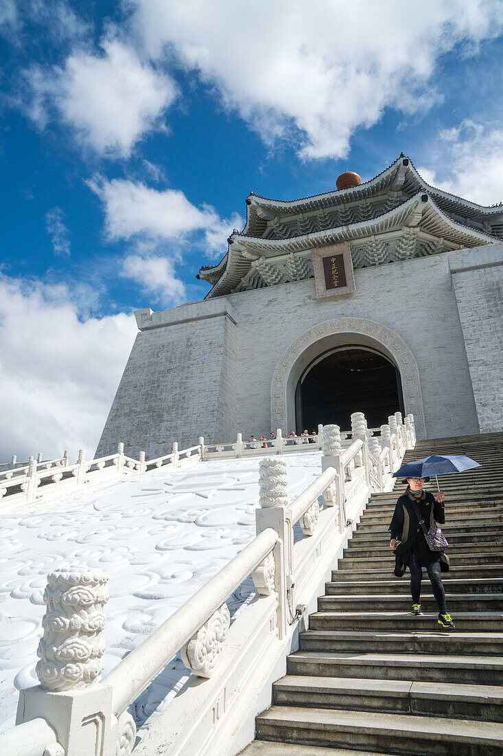 Frau mit sonnenschirmenden Regenschirm kommt die Treppe hinunter, die zur Chiang Kai-Shek Memorial Hall, Taipei, Taiwan, Asien führt