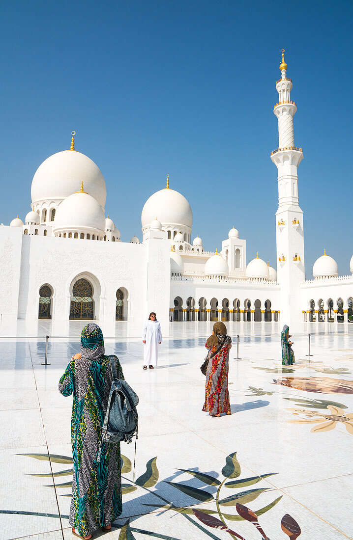 Touristen, die vollständig von religiösen Regeln gedeckt sind, fotografieren das Innere der Scheich Zayed Grand Mosque, Abu Dhabi, Vereinigte Arabische Emirate, Mittlerer Osten