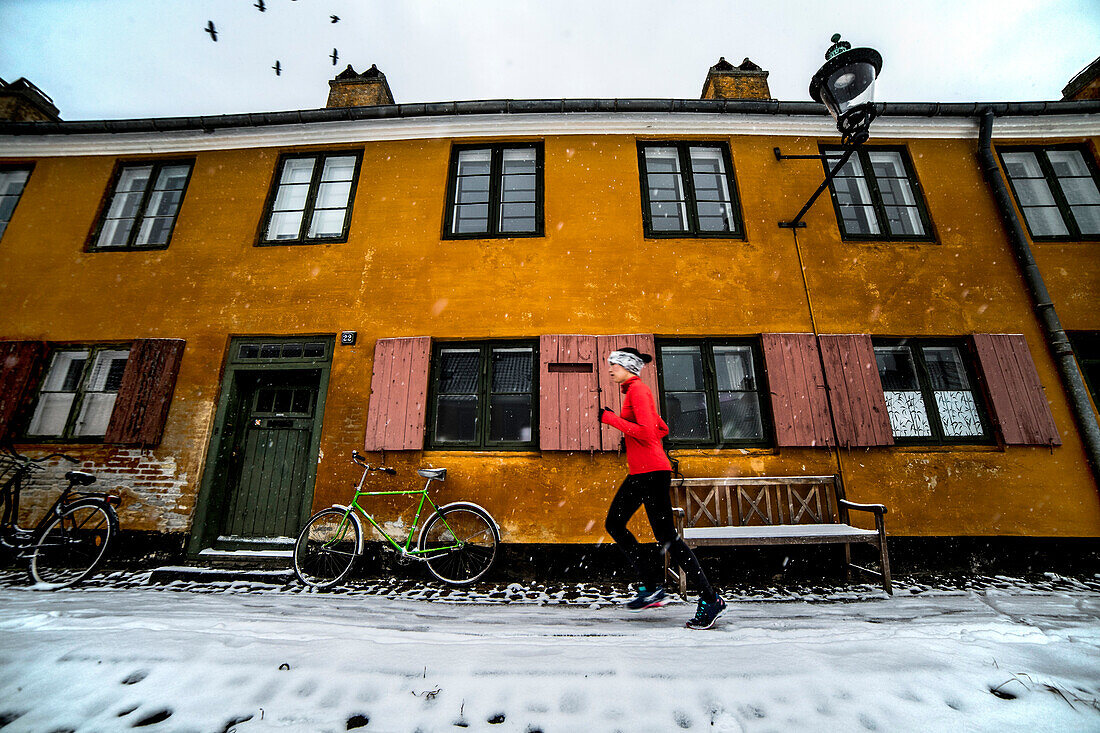 Woman jogging outside historic building inÂ CopenhagenÂ in winter