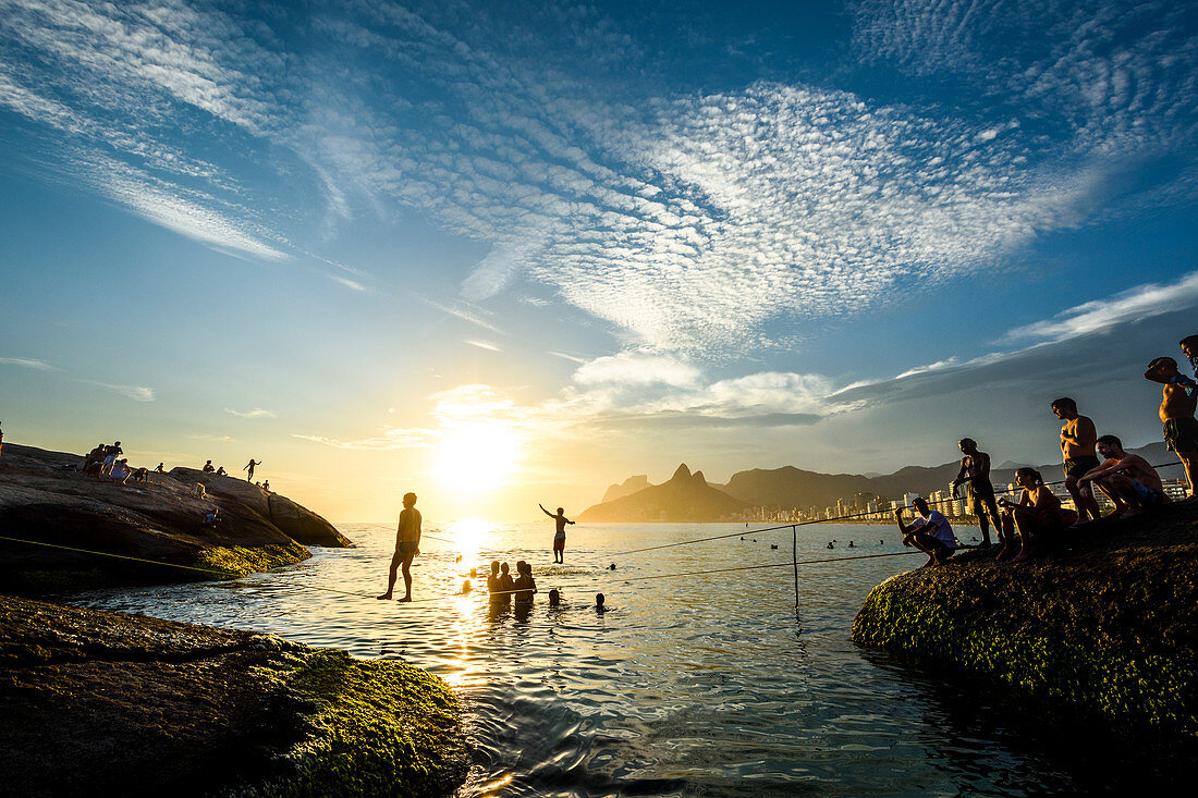 Slacklining in Arpoador Strand während des Sonnenuntergangs, Rio De Janeiro, Brasilien