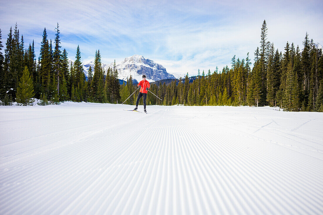 Langlauf-Skifahrer folgt gepflegten Skipiste, Wald