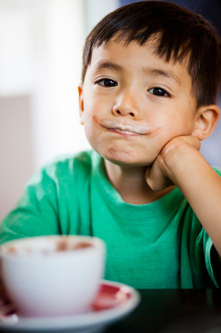 Ein japanischer amerikanischer vierjähriger Junge trinkt eine Heißschokolade.