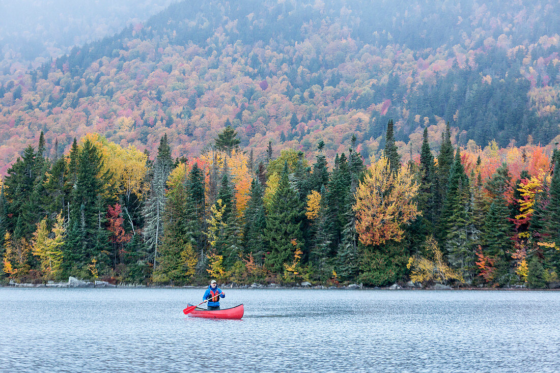 Ein Mann Kanu auf Greenough Teich im Herbst bei Wentworths Lage, New Hampshire