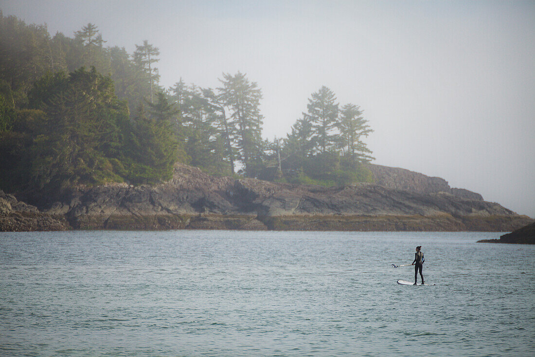 A young woman paddles a SUP in Pacific Rim National Park, Vancouver Island, British Columbia