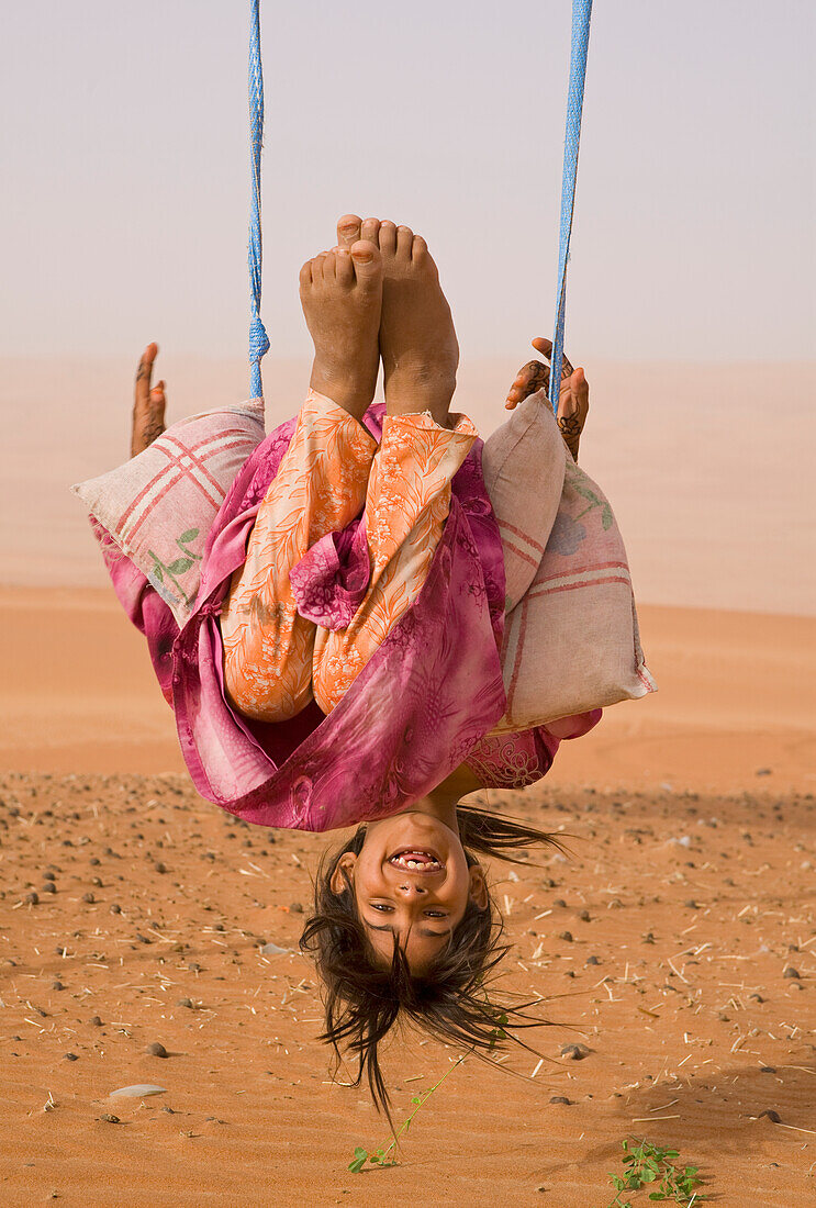 'Ein junges Bedu Mädchen spielt auf ihrem Wüstenschwingen; Wahiba Sands, Oman'