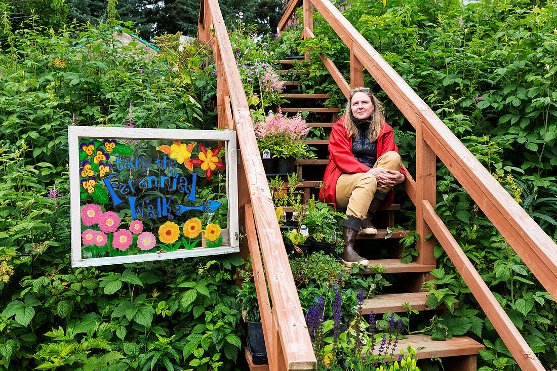 Frau sitzt auf Treppen in einem üppigen Garten, Seldovia, South Central Alaska, USA
