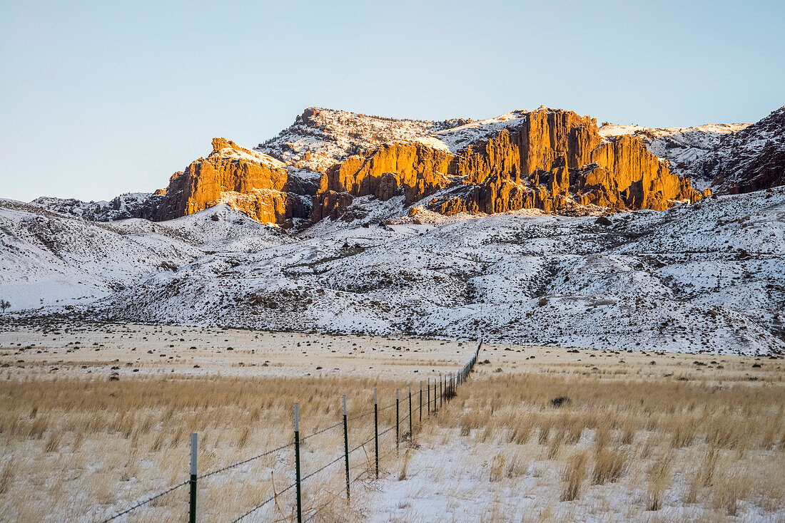 'Stacheldrahtzaun überqueren Feld in Richtung schroffe Berge in der Nähe von Cody; Wyoming, Vereinigte Staaten von Amerika'