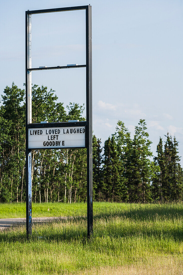 'A old retail sign along the road with a message showing that they have left the premises; Alberta, Canada'
