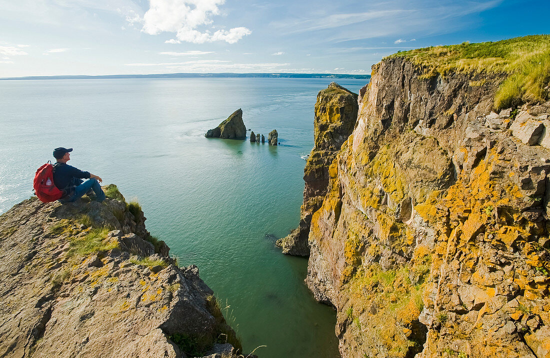 'A hiker looks out over the Bay of Fundy from Cape Split; Nova Scotia, Canada'