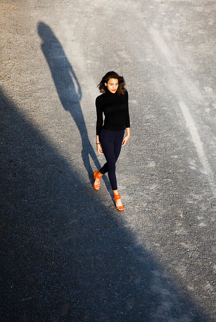 Portrait der überzeugten jungen erwachsenen Frau in schwarzen Kleidern und orange Schuhe Gehen, High Angle View