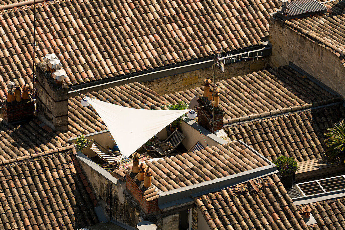 Terrace with sun deck and sunsail in the middle of French tiled roofs