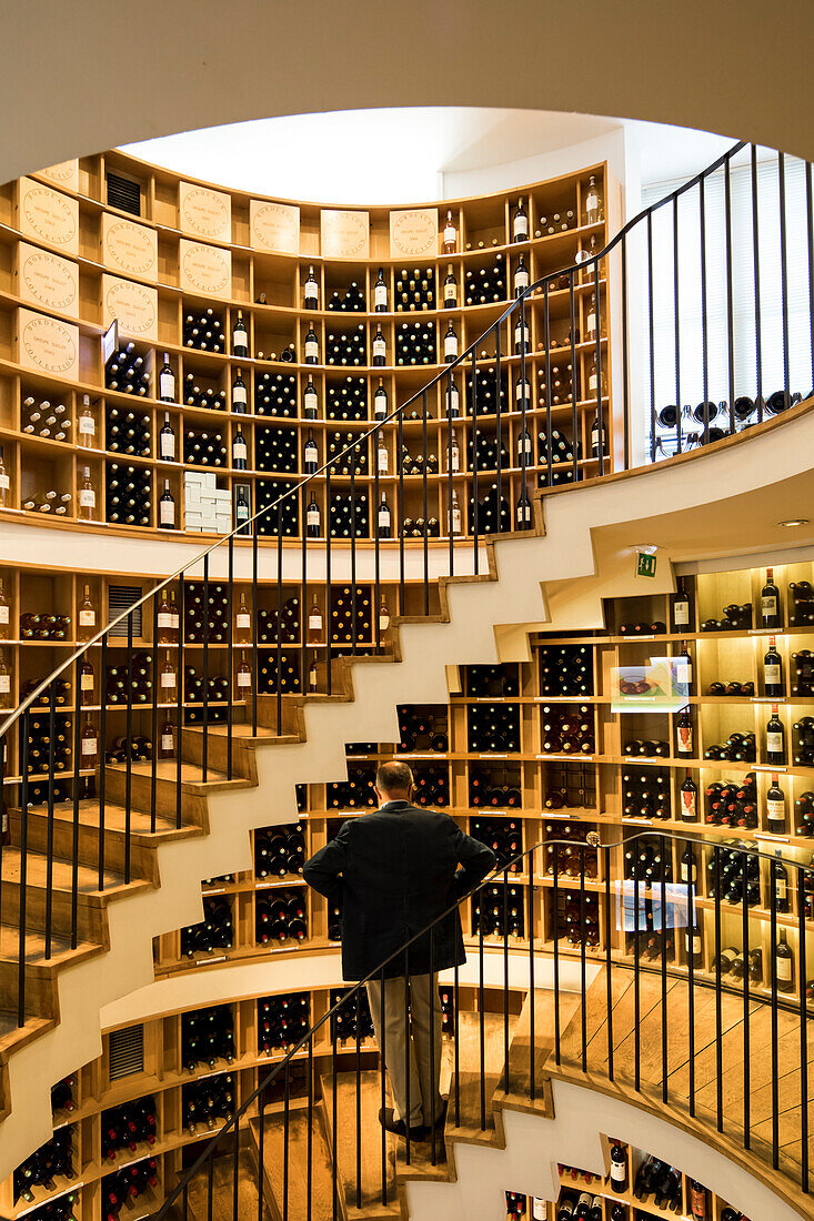 A man stands in front of the large selection in L'Intendant  wine shop