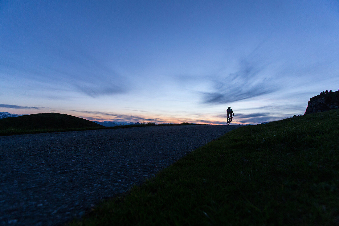 Junger Mann auf seinem Rennrad bei Sonnenuntergang in den Kitzbühler Alpen, Kitzbühlerhorn, Tirol, Österreich
