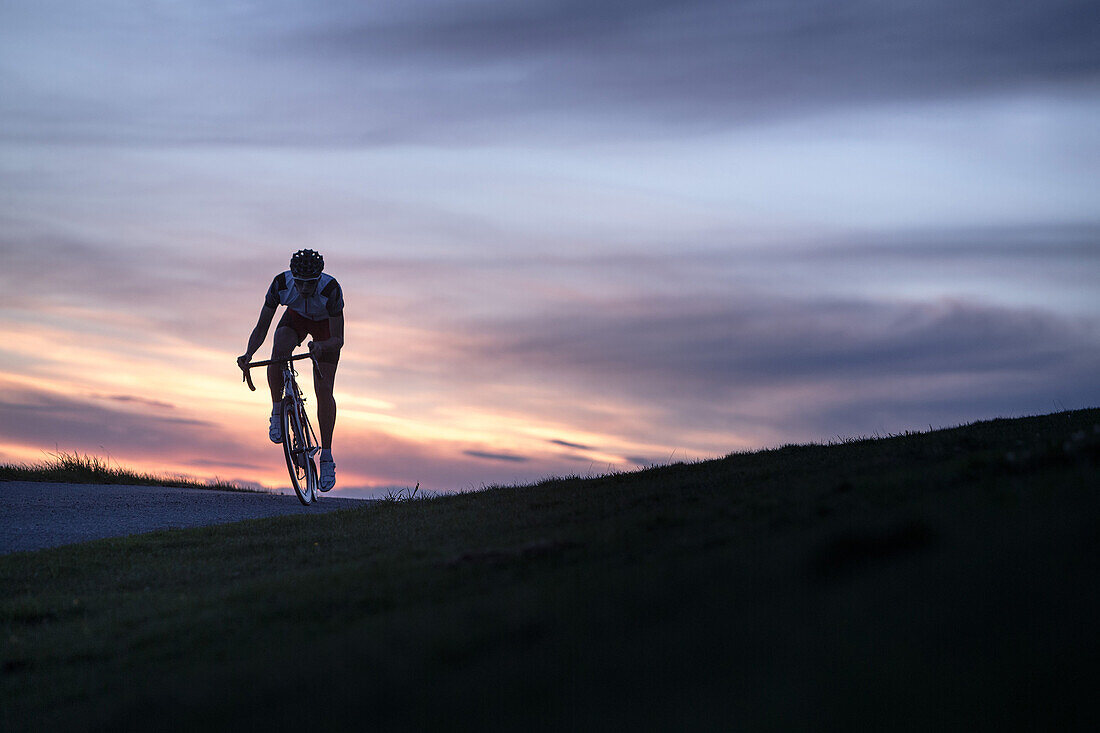 Junger Mann auf seinem Rennrad bei Sonnenuntergang in den Kitzbühler Alpen, Kitzbühlerhorn, Tirol, Österreich