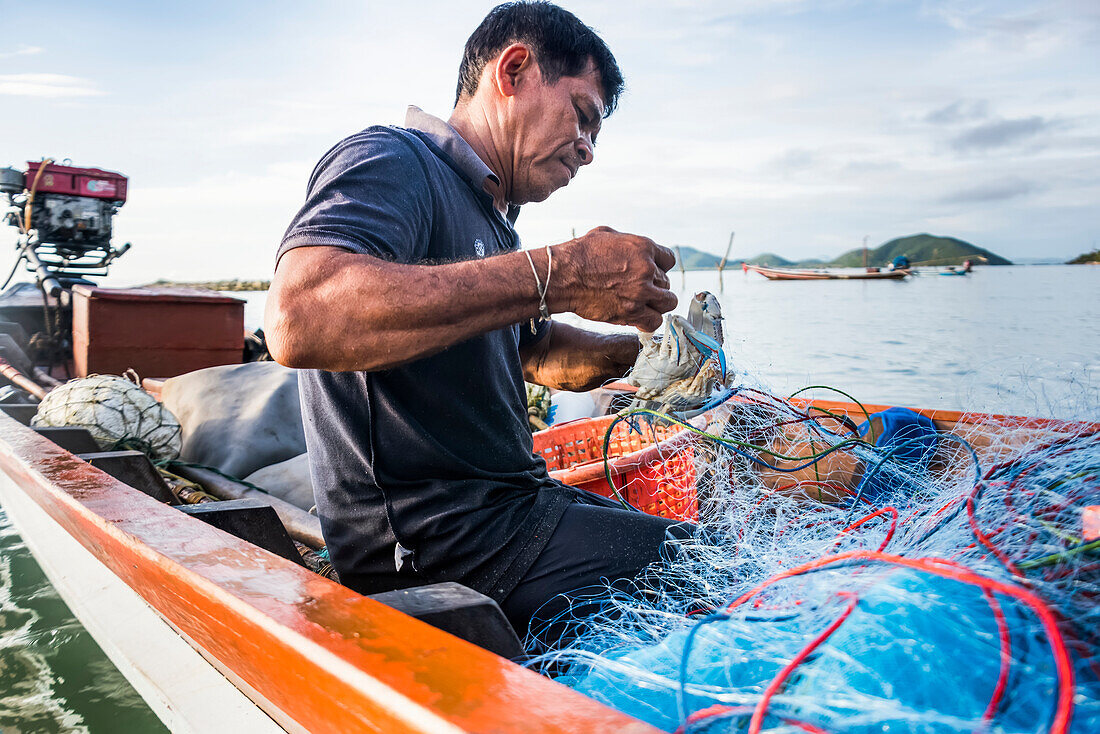 'Ein Fischer, der mit Netzen auf seinem Fischerboot arbeitet; Ko Samui, Chang Wat Surat Thani, Thailand'