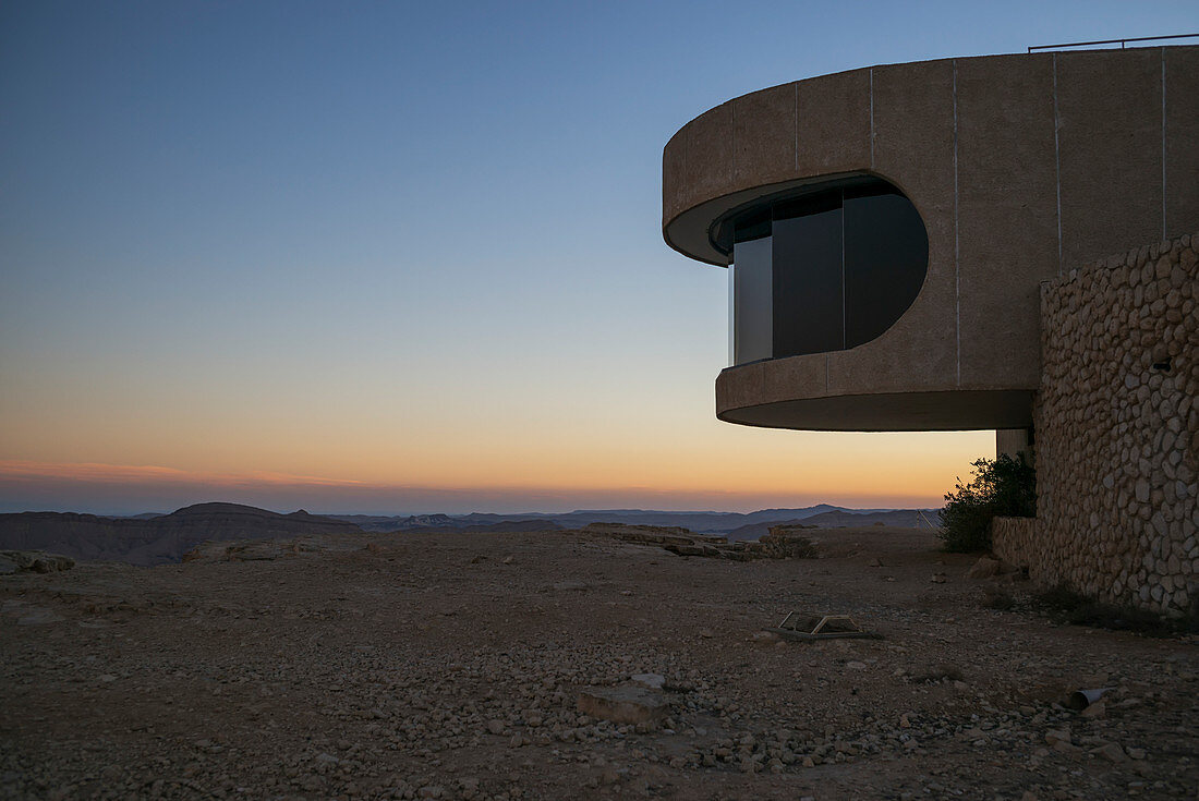 'Ein bunter Sonnenuntergang über dem Horizont mit einem Sichtfenster entlang eines geschwungenen Gebäudes für einen Blick; Mitzpe Ramon, Süddistrikt, Israel'