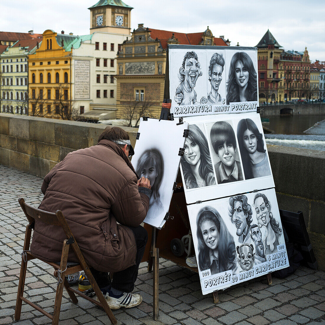'Ein Straßenkünstler zieht schwarze und weiße Porträts auf Frauen; Prag, Tschechische Republik'