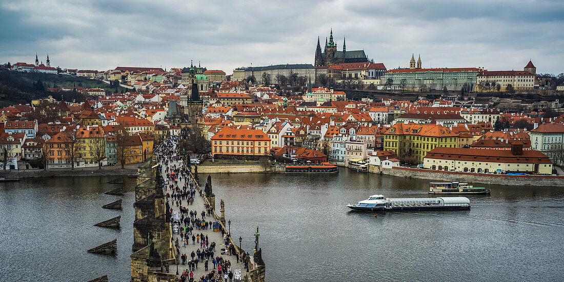 'Pedestrians on Charles Bridge over the Vltava River and Prague Castle in the distance; Prague, Czech Republic'