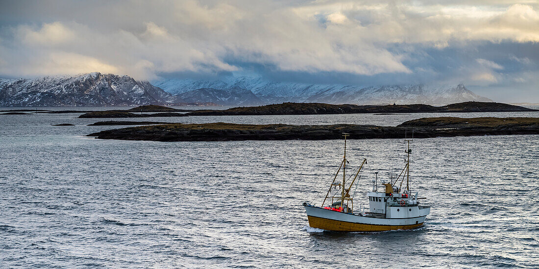 'A commercial fishing boat in the atlantic ocean in the Arctic with a view of the mountianous landscape; Norland, Norway'