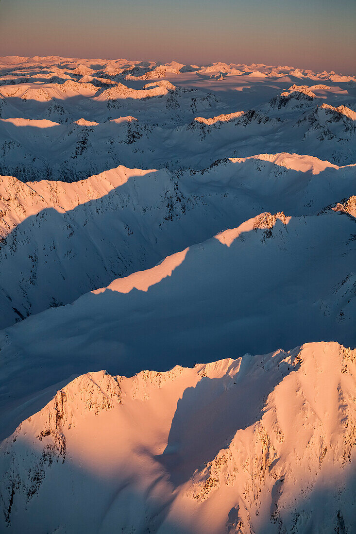 Peaks of a snow covered mountain range glowing pink at sunset, Kachemak Bay State Park, Alaska, United States of America