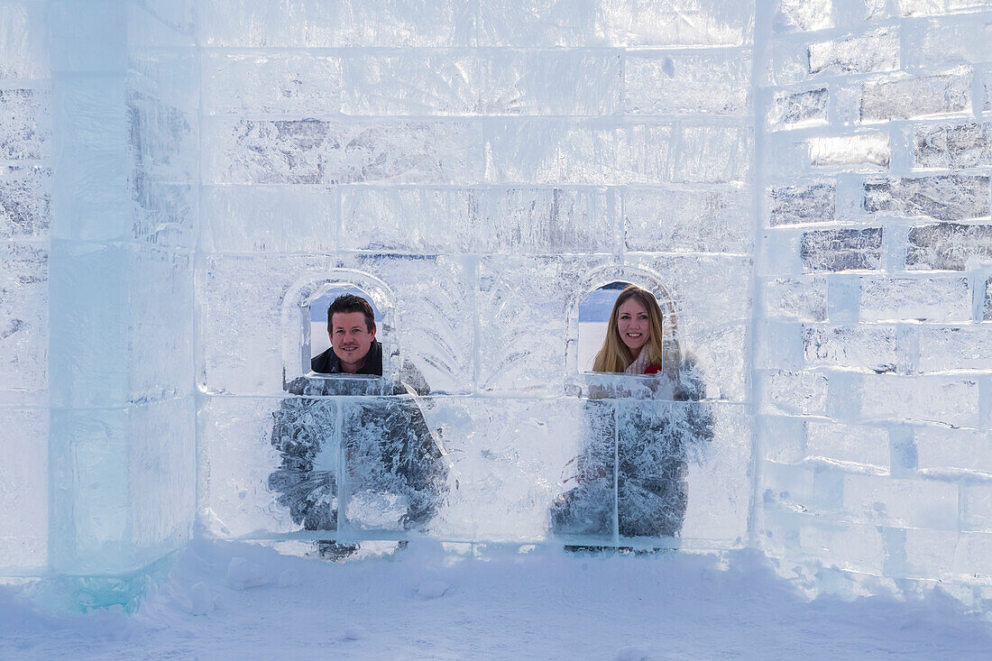 Ein junges Touristenpaar posiert innerhalb eines Eisschlosses auf dem Eis am Lake Louise im Banff Nationalpark aufbauen, Lake Louise, Alberta, Kanada