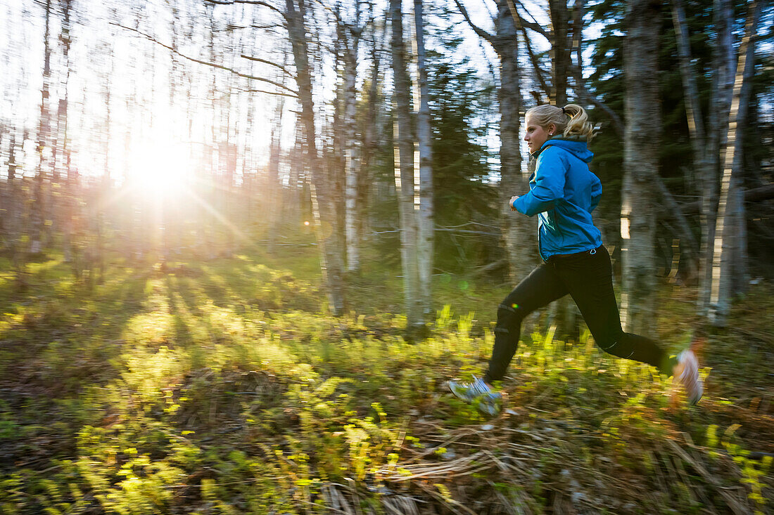 Eine junge Frau, die über die Pflanzen des Waldbodens in einem Wald läuft, Homer, Alaska, Vereinigte Staaten von Amerika