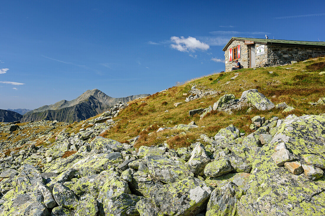 Person sitting in front of hut Mindener Huette, hut Mindener Huette, Tauern ridgeway, High Tauern range, Salzburg, Austria
