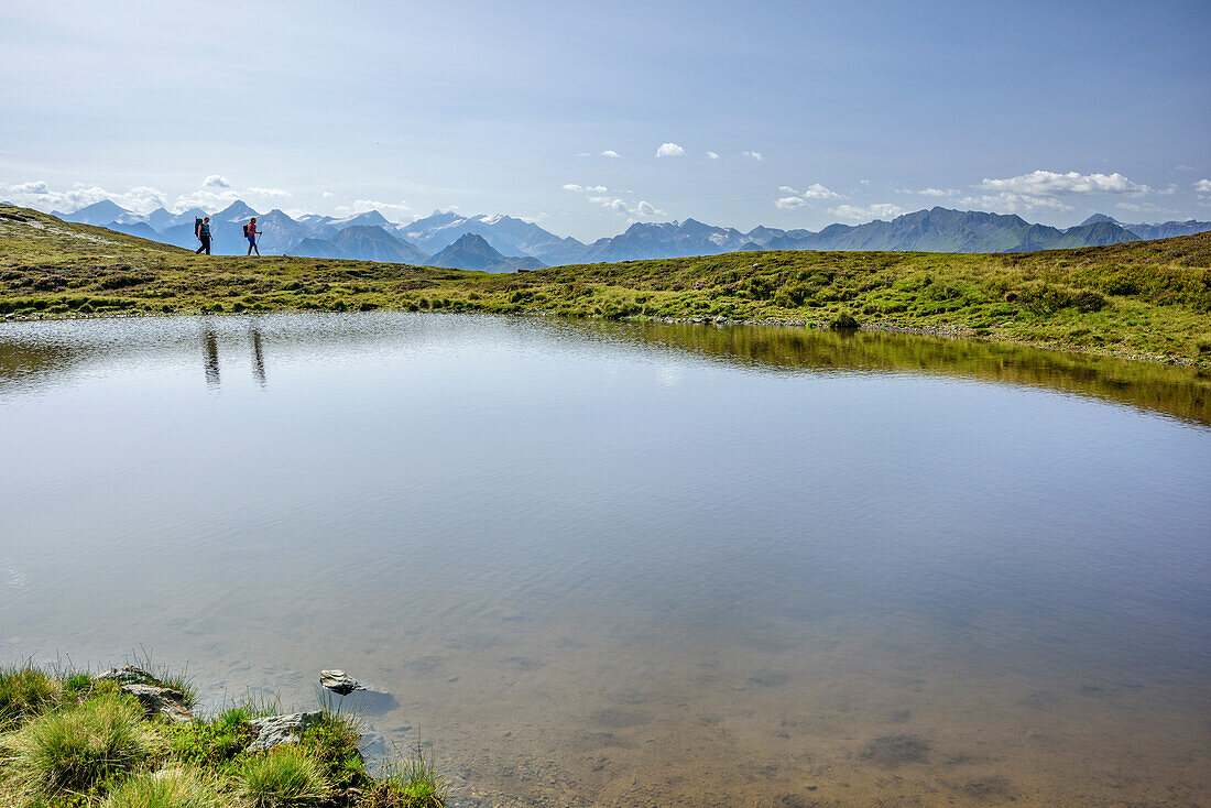 Zwei Personen wandern an See entlang, Hohe Tauern im Hintergrund, Pinzgauer Spaziergang, Kitzbüheler Alpen, Salzburg, Österreich