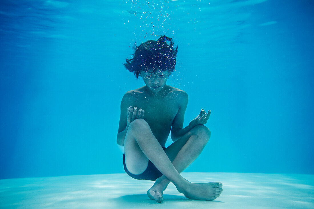 Junge ruht im Lotussitz unter Wasser