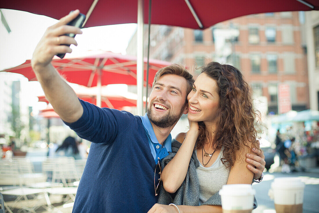 Paar posiert für ein Selfie im Café im Freien