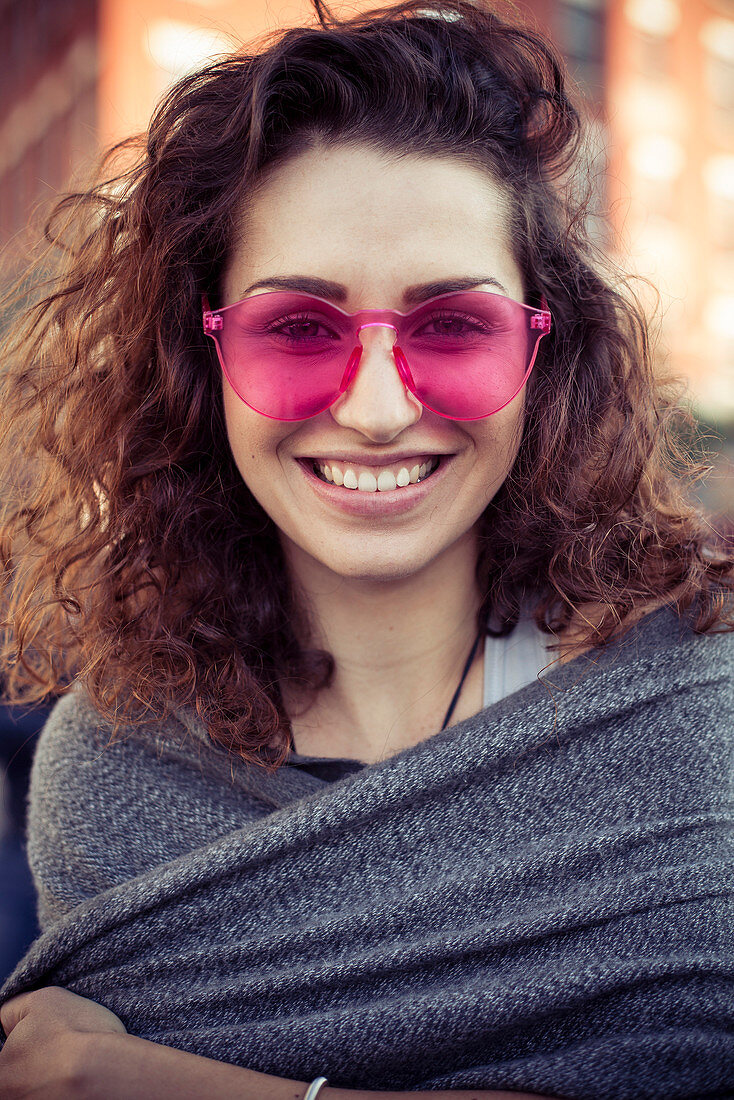 Frau trägt rosa Sonnenbrille, fröhlich lächelnd, Porträt