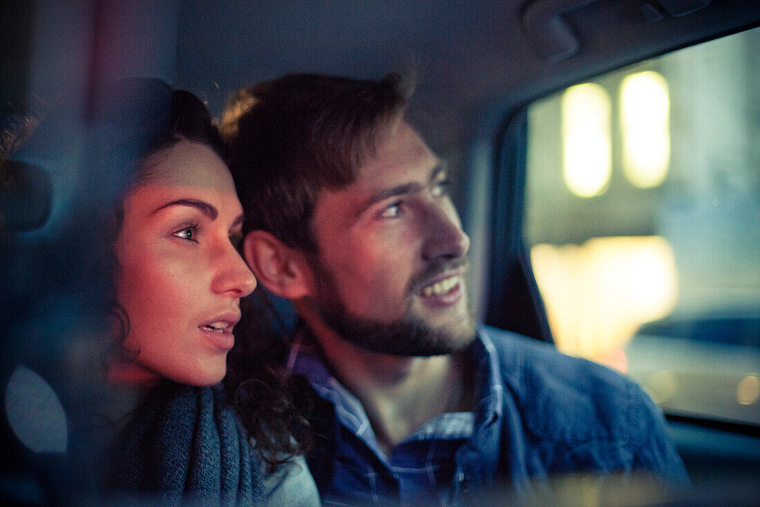 Couple looking out car window at night