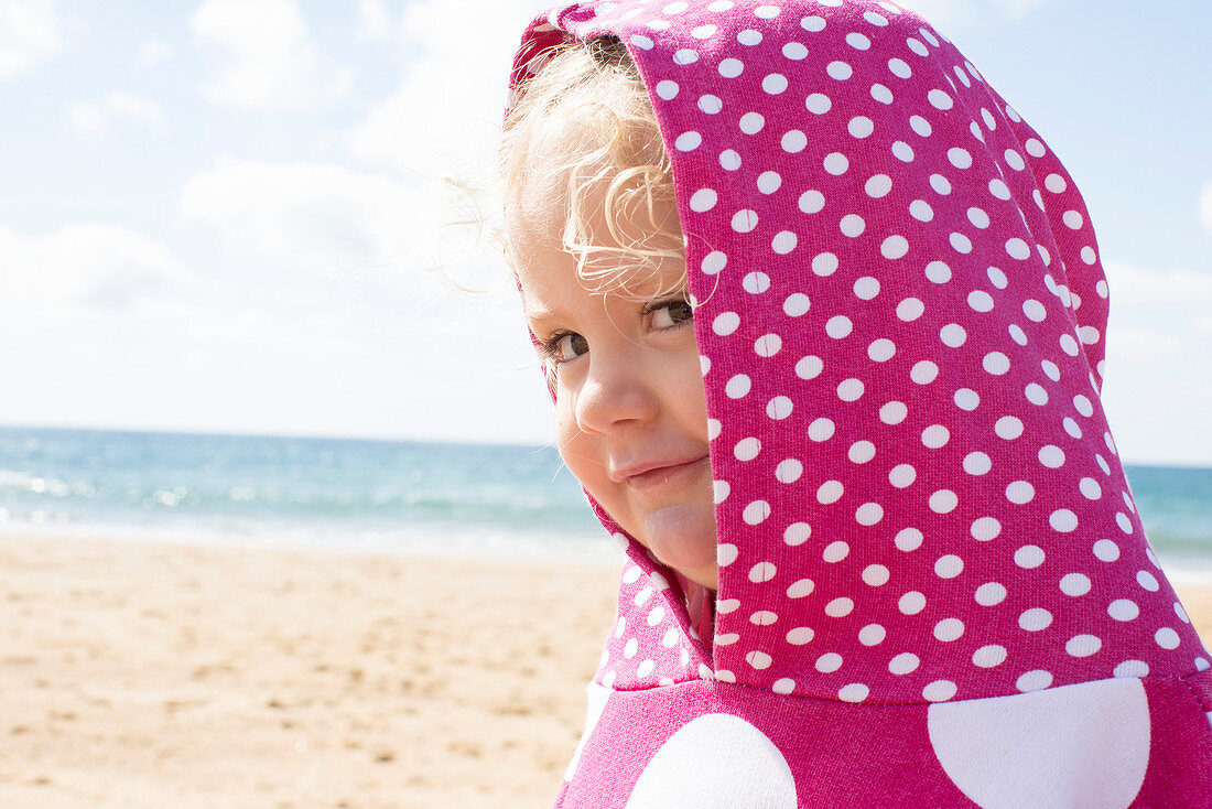 Mädchen trägt Kapuze mit Polka Dots am Strand