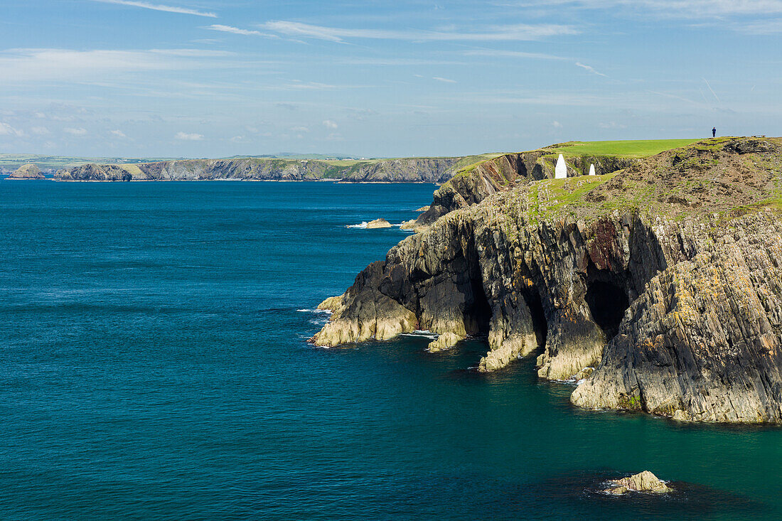 A solitary walker perched high on the cliffs stretching for miles along the Pembrokeshire coast path on a calm summers day, Wales, United Kingdom, Europe