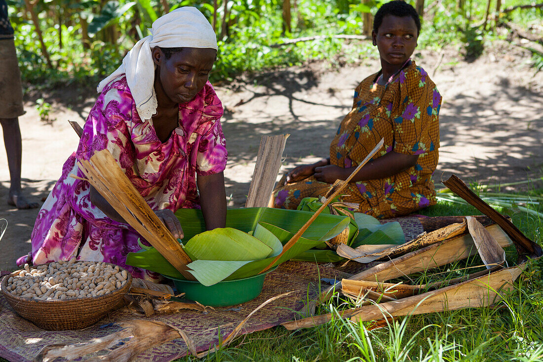 A woman wraps some groundnuts in a banana leaf, Uganda, Africa