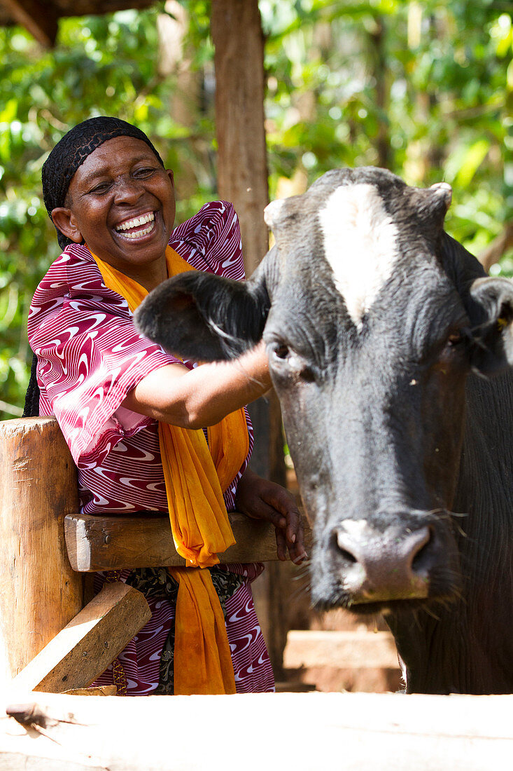 A woman smiling next to her cow, Uganda, Africa