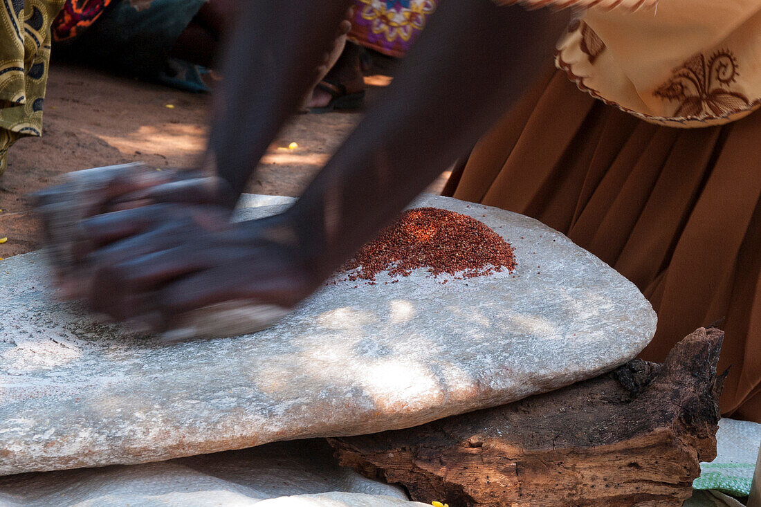Eine Frau, die zwei Steine ??benutzt, um Korn zu mahlen, Uganda, Afrika