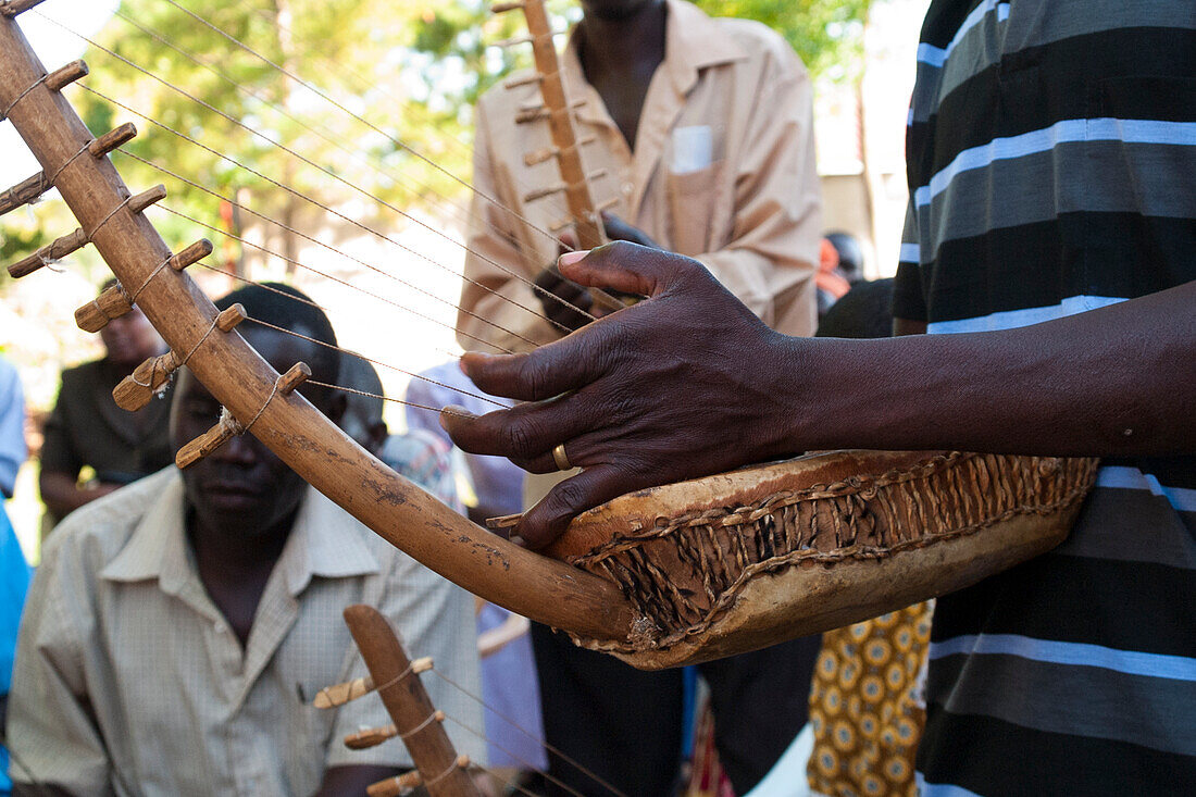 Eine Gruppe Männer, die das Chordophon spielen, das ein Musikinstrument von der Harfenfamilie, Uganda, Afrika