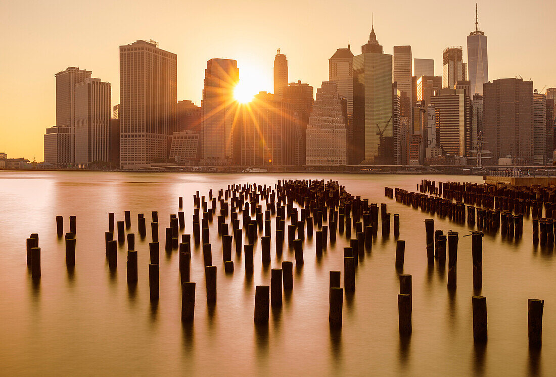 Lower Manhattan skyline, New York skyline, exposed wooden pier stumps, at sunset, East River, New York, United States of America, North America