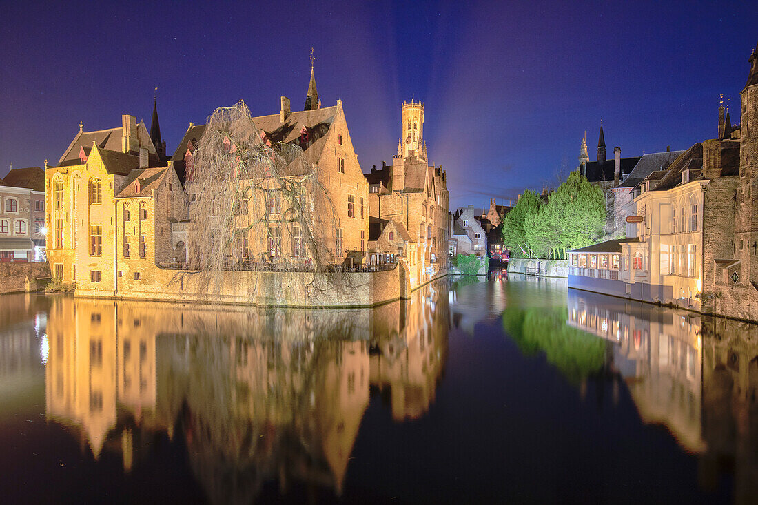 Der mittelalterliche Glockenturm und historische Gebäude spiegeln sich am Rozenhoedkaai-Kanal bei Nacht, UNESCO-Weltkulturerbe, Brügge, Westflandern, Belgien, Europa