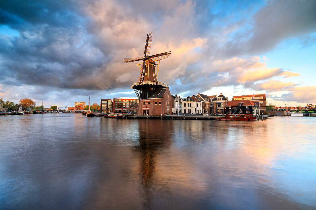 Rosa Wolken bei Sonnenuntergang auf der Windmühle De Adriaan spiegelt sich im Fluss Spaarne, Haarlem, Nord-Holland, Niederlande, Europa