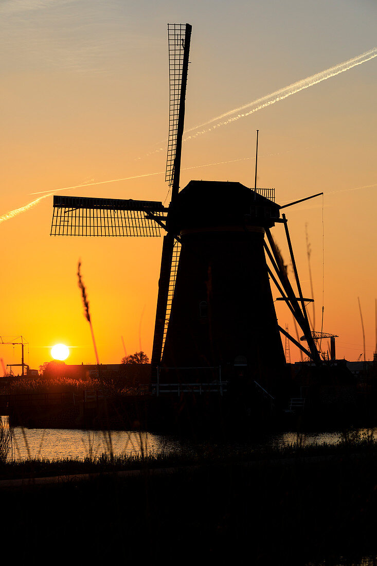 Silhouette der typischen Windmühle umrahmt vom feurigen Himmel bei Sonnenuntergang, Kinderdijk, UNESCO-Weltkulturerbe, Molenwaard, Südholland, Niederlande, Europa